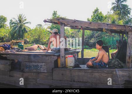 Fiume Hau, Vietnam - 8 marzo 2019: Uomini e ragazzi vietnamiti locali su una barca tradizionale lungo il fiume Hau (Bassac) presso il delta del Mekong vicino a Can Tho, V. Foto Stock