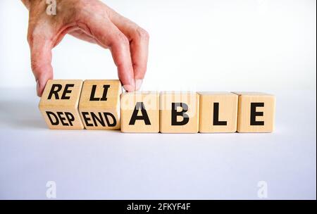 Simbolo affidabile o affidabile. Uomo d'affari gira i cubetti di legno e cambia la parola affidabile ad affidabile. Splendido sfondo bianco, spazio per la copia. Autobus Foto Stock