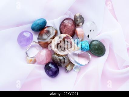 Gemme e cristalli tumbled e ruvidi di vari colori. Ametista, quarzo rosa, agato, apatite, aventurina, olivina, turchese, acquamarina, roccia cr Foto Stock