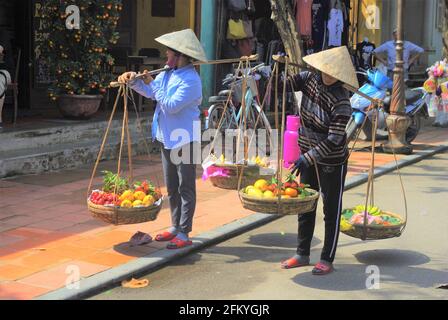 Venditori di frutta di strada con cestini di trasporto tradizionali, Hoi An, Vietnam, Asia Foto Stock