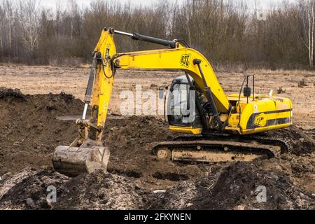 Bielorussia, regione di Minsk - 11 dicembre 2019: L'uomo addetto alle costruzioni su un escavatore cingolato scava una trincea in un'area industriale. Scavo con Foto Stock