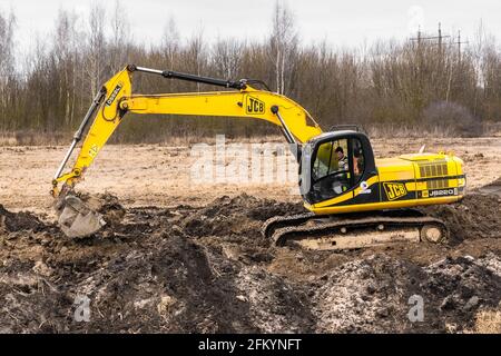 Bielorussia, regione di Minsk - 11 dicembre 2019: L'uomo addetto alle costruzioni su un escavatore cingolato scava una trincea in un'area industriale. Scavo con Foto Stock