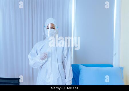Ritratto di giovane donna asiatica medico che indossa tuta protettiva PPE con visiera protettiva e maschera con tampone in cotone per test per coronavirus mentre si trova in ospedale Foto Stock