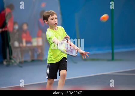 Un ragazzo con una racchetta da tennis sul campo gioca a tennis. Foto Stock