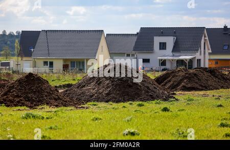 Lipsia, Germania. 03 maggio 2021. Pile di terra si trovano in un campo tra altre case distaccate durante il lavoro di sviluppo per una nuova tenuta di alloggi. Uno sviluppatore sta sviluppando un'altra area per nuove case qui nella parte occidentale di Lipsia. Credit: Jan Woitas/dpa-Zentralbild/ZB/dpa/Alamy Live News Foto Stock