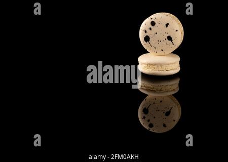 Macaroon di gruppo su fondo di vetro nero con riflessione. Foto Stock