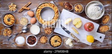 Torte fatte in casa, dolci al forno con ingredienti da cucina: ciambelle di mele, muffin e pasticcini su sfondo di legno. Vista dal piano d'esame, disposizione piatta. Foto Stock