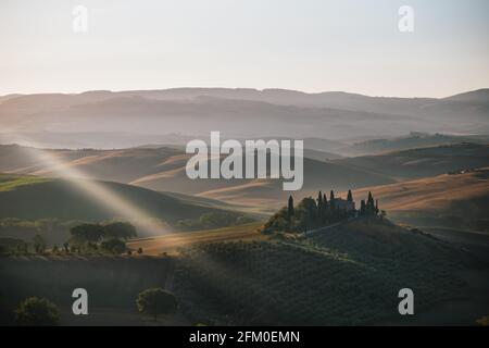 San Quirico d'Orcia - Agosto 20 2020: Podere Belvedere Villa in Val d'Orcia in Toscana, Italia all'alba o all'alba, con un raggio di luce in epoca romana Foto Stock