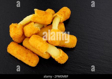 Gruppo di grattugiate di mozzarella ricoperte di pane su un'ardesia sfondo di pietra Foto Stock