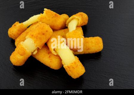 Gruppo di grattugiate di mozzarella ricoperte di pane su un'ardesia sfondo di pietra Foto Stock