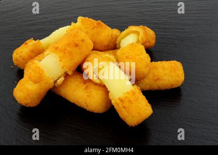 Gruppo di grattugiate di mozzarella ricoperte di pane su un'ardesia sfondo di pietra Foto Stock