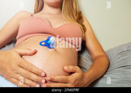 Foto di una donna incinta con succhietto sul ventre Foto Stock