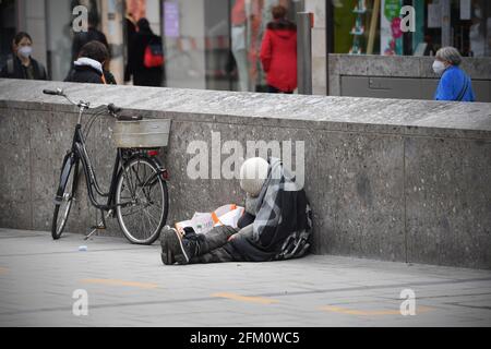 Monaco, Germania. 05 maggio 2021. Vita pubblica in tempi della pandemia di coronavirus a Monaco. Una persona mendicante, senza casa, bum si addormenta a terra e si appoggia contro un muro. | utilizzo in tutto il mondo credito: dpa/Alamy Live News Foto Stock