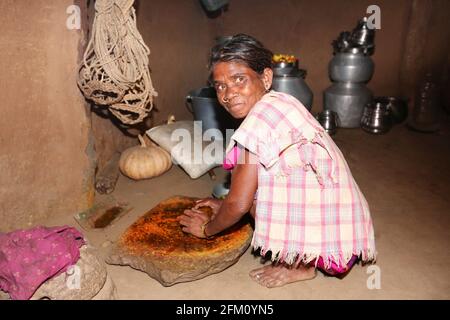 Vecchia donna tribale usando un macinacaffè tradizionale della pietra per macinare il peperoncino rosso al villaggio di Boriborivalsa, Araku, Andhra Pradesh, India. TRIBÙ PARANGIPERJA Foto Stock