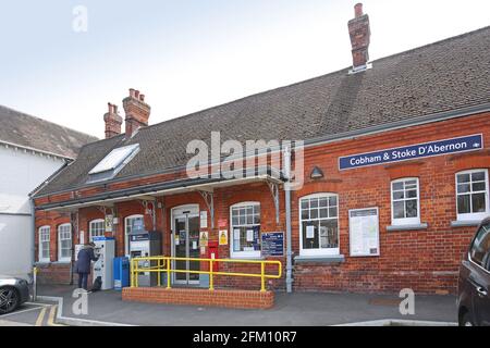 Ingresso alla stazione di Cobham e Stoke D'Abernon, Surrey. Tipica stazione vittoriana nei sobborghi di Londra, Regno Unito. Mostra il passeggero che utilizza una macchinetta per biglietti. Foto Stock