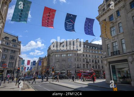 Bandiere che soffiano in vento frettoloso il 4 maggio 2021 sopra Oxford Circus come una Londra centrale più affollato esce da hard Covid Lockdown, Regno Unito Foto Stock