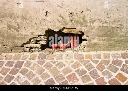 Tubi in pvc rosso tagliati sotto il muro di una vecchia casa in mattoni vicino alla strada (Pesaro, Italia, Europa) Foto Stock
