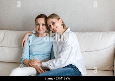 Due donne adulte sono sedute sul divano e guardano la telecamera. Foto Stock