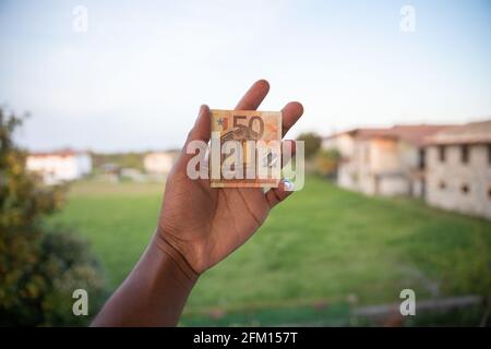 banconota da 50 euro strappata a metà tenuta in mano da un ragazzo Foto Stock