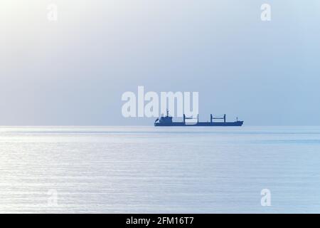 Orizzonte del mare con silhouette della nave da carico. Mare sereno e sereno senza fine. Messa a fuoco morbida selettiva Foto Stock