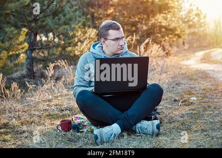 Autoisolamento, distrazioni a casa concetto. Scollegare dopo il lavoro, lavorando troppo concetto. Gli uomini fuori sulla natura con il notebook è al lavoro. . Foto Stock