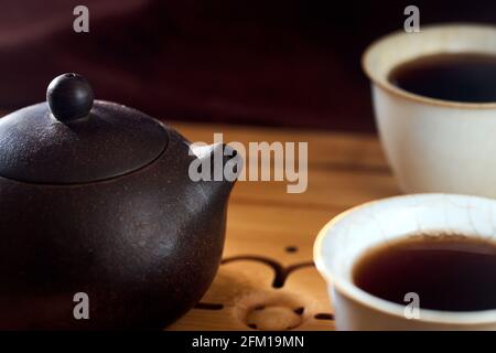 Cerimonia del tè gong fu cha. Teapot cinese di argilla di yixing viola fatto a mano con pu pu erh e due ciotole di porcellana di ceramica di celadon tazza di tè su bambù Foto Stock