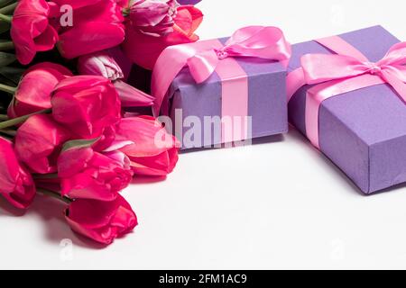Tulipani e confezioni regalo lilla con un posto per il testo su sfondo bianco. Tessera verticale vacanza per iscrizione Foto Stock