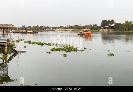 Un rimorchiatore sta trainando la grande barca di carico piena di sabbia nel grande fiume al cantiere vicino al fiume, vista frontale con lo spazio di copia. Foto Stock