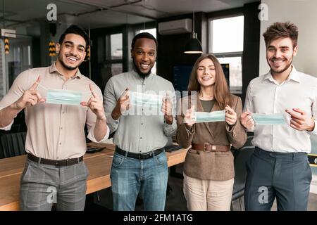 Persone internazionali che indossano maschere mediche un ufficio Foto Stock