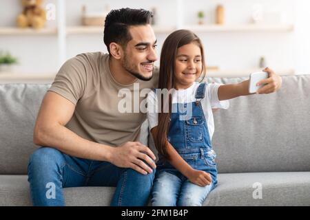 Il padre allegro che prende selfie con la figlia carina Foto Stock