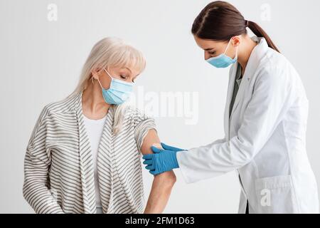 Donna anziana che riceve il vaccino di Coronavirus per iniezione intramuscolare Foto Stock