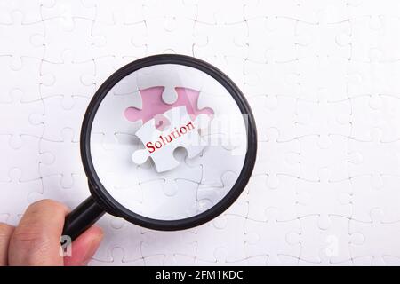 Lente d'ingrandimento su puzzle puzzle: Soluzione Foto Stock