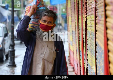 Srinagar, India. 05 maggio 2021. Kashmiri uomo musulmano indossando maschera protettiva cammina oltre i negozi chiusi nel centro della città di Srinagar durante il blocco imposto dalle autorità il 5 maggio 2021. Jammu & Kashmir registra 52 morti che è il maggior numero di decessi correlati COVID -19 nella regione. L'India riporta 382,315 casi di Covid-19 e 3,780 nuovi decessi. (Foto di Najmus Saqib/INA Photo Agency/Sipa USA) Credit: Sipa USA/Alamy Live News Foto Stock