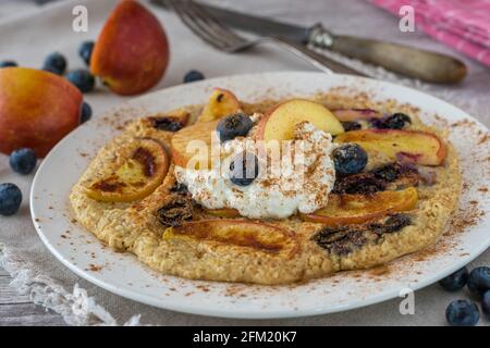 Frittella di farinata d'avena fresca e deliziosa, senza glutine, cotta con mele e mirtilli e condito con formaggio di cottage ad alta proteina e. cannella Foto Stock