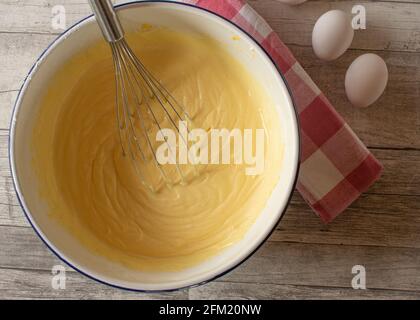 Cheesecake appena mescolata ripieno in una ciotola bianca rustica di smalto Su legno Tavola sfondo da sopra Foto Stock