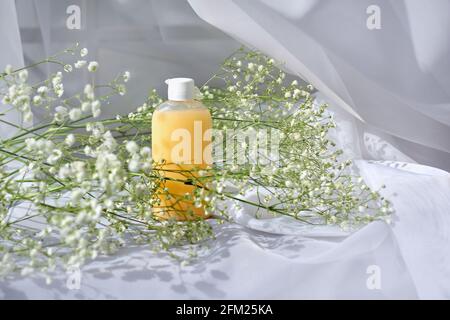 mock up gel o shampoo bottiglia e fiori gypsophila su sfondo bianco. Concetto di cosmetici naturali eco-biologici spa. Foto Stock