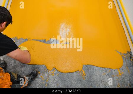 Lavoratore che applica pavimenti in resina epossidica e poliuretanica system.These prodotti facili da pulire hanno anche caratteristiche antiscivolo. Foto Stock