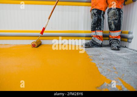 Lavoratore che applica pavimenti in resina epossidica e poliuretanica system.These prodotti facili da pulire hanno anche caratteristiche antiscivolo. Foto Stock