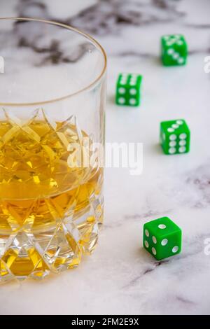 Vista dall'alto di cristallo con whisky su tavolo in marmo bianco con dadi verdi, fuoco selettivo, verticale, con spazio per la copia Foto Stock