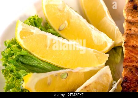 Primo piano di fette di limone e foglie di lattuga. Macro. Può essere utilizzato come sfondo completo. Foto Stock