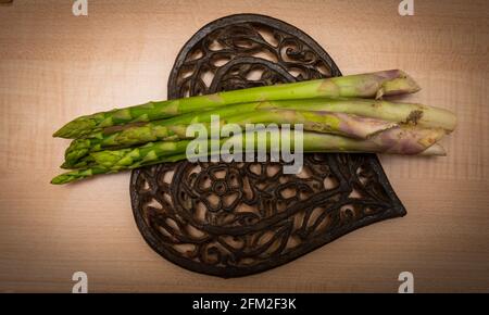 Cesoie di asparagi su tagliere di legno con fondo a forma di cuore. Concetto di alimentazione sana. Foto Stock