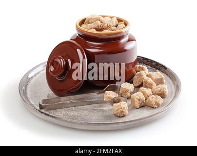 Cubetti di zucchero di canna di covata nel recipiente dello zucchero su ceramica piastra isolata su sfondo bianco Foto Stock
