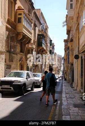 Valletta. Malta. Strada stretta nella Città Vecchia con tipica architettura maltese: Edifici in pietra calcarea con balconi in legno recintati. Foto Stock