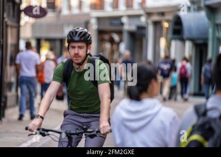 Un ciclista in un casco guida lungo Cambridge Street. Sfocatura del movimento. Cambridge, Regno Unito, 1 agosto 2019. Foto Stock