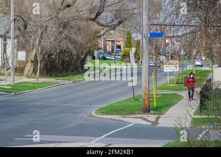 Toronto, Canada, 2021 aprile - Vicino al quartiere desertato durante il blocco della pandemia in Ontario. Donna che indossa la maschera cammina da sola Foto Stock