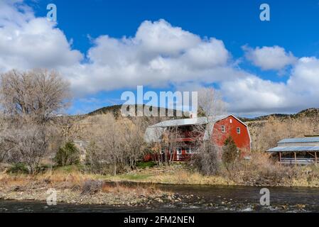 Una casa in stile granaio rosso vicino ad un fiume. Colorado, Stati Uniti. Foto Stock