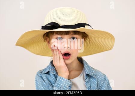 Primo piano ritratto di carina bambina in cappello beige con sorpresa emozione. Foto Stock