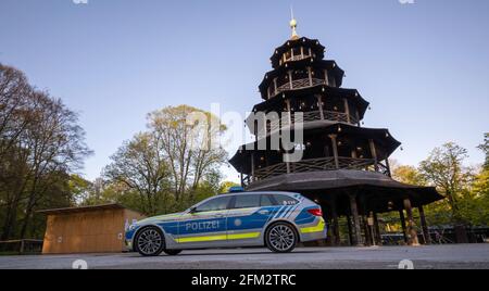 Monaco, Germania. 05 maggio 2021. Una macchina di polizia passa davanti alla birreria all'aperto presso la Torre Cinese nel Giardino Inglese. Credit: Peter Kneffel/dpa/Alamy Live News Foto Stock