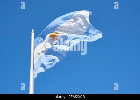 Bandiera argentina che vola su un palo contro un cielo blu in una giornata di sole. Simbolo patriottico dell'Argentina Foto Stock