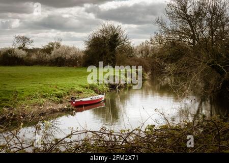 Camminando sulla Ouse Way, Barcombe Mills, Inghilterra, una piccola barca ormeggiata sulla riva Foto Stock